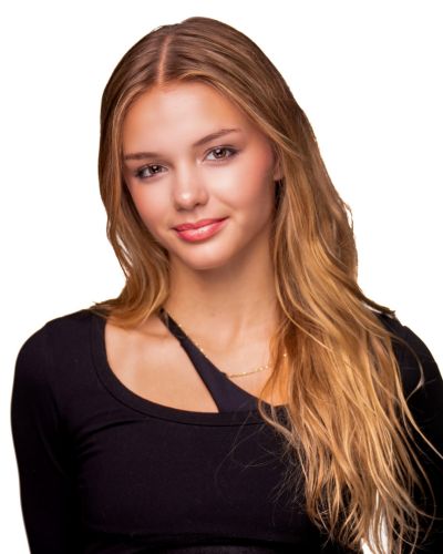 A young woman with long, wavy blonde hair wearing a black top, smiling softly at the camera against a plain white background.